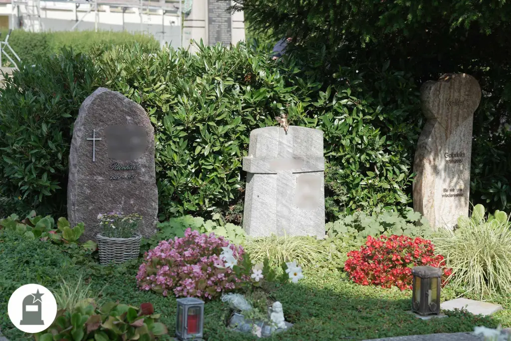 Drei Grabmale aus Naturstein mit roten und rosa Blumen
