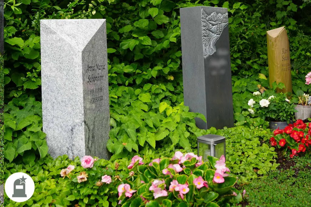 Zwei Grabstelen aus Granit mit rosa Blüten davor