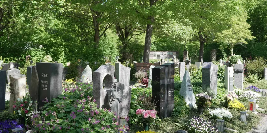 Grabmale zwischen blühenden Beeten am Friedhof Untergrombach