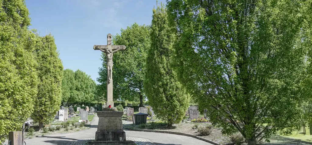 Friedhofskreuz Obergrombach zwischen hohen Bäumen