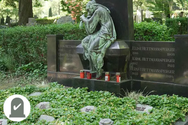 Historisches Grabmal mit Bronzefigur und Grablichtern