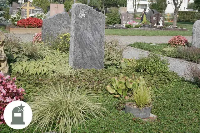 Grabstelen aus Naturstein zwischen Gräsern