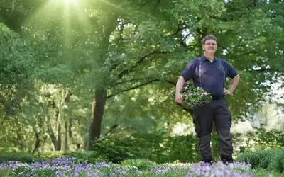 Johannes Siegele mit einer Pflanzschale zwischen blühenden Beeten